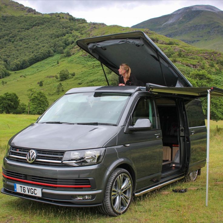 a van is parked in the grass with its open hood on it's roof