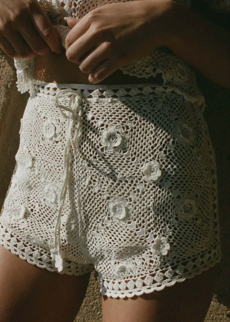 a close up of a person wearing crochet shorts and holding something in their hand