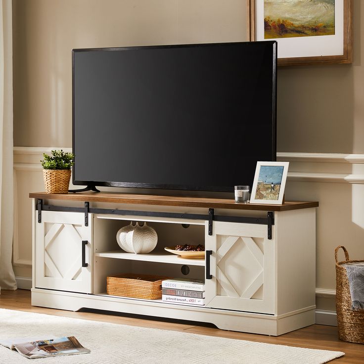 a flat screen tv sitting on top of a wooden entertainment center in a living room