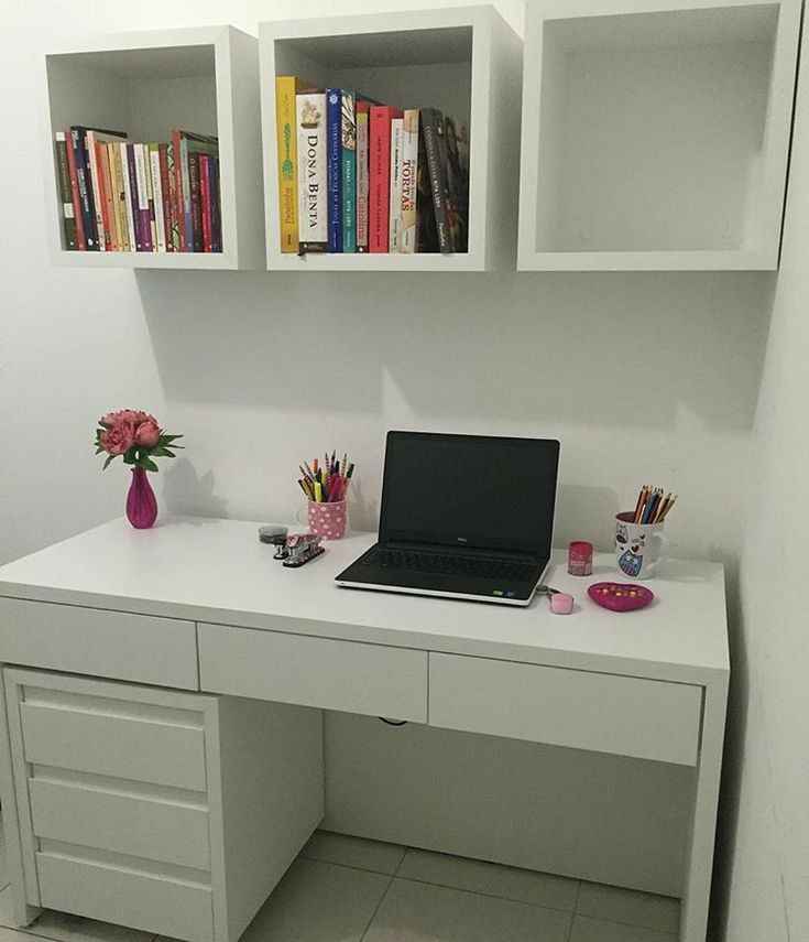 a laptop computer sitting on top of a white desk next to a book shelf filled with books