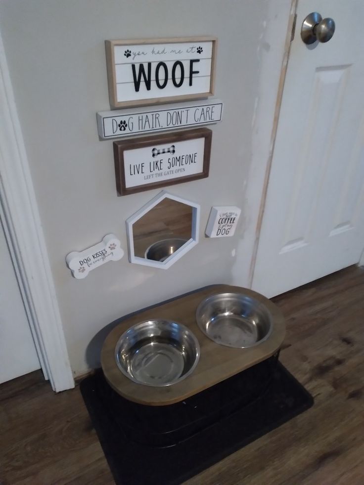 a dog's house with two bowls on the floor and a sign that says woof