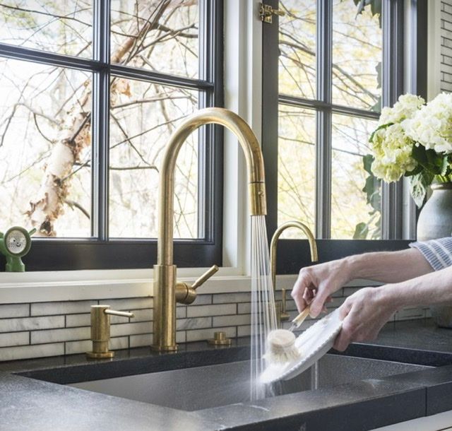 a woman is washing her hands in the kitchen sink while holding a rag over the faucet