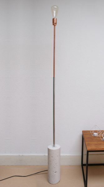 a floor lamp sitting on top of a wooden table next to a small table with a vase