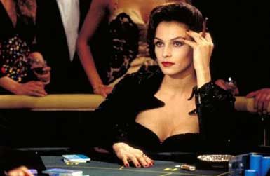 a woman sitting at a casino table with her hand on her face and other people standing around