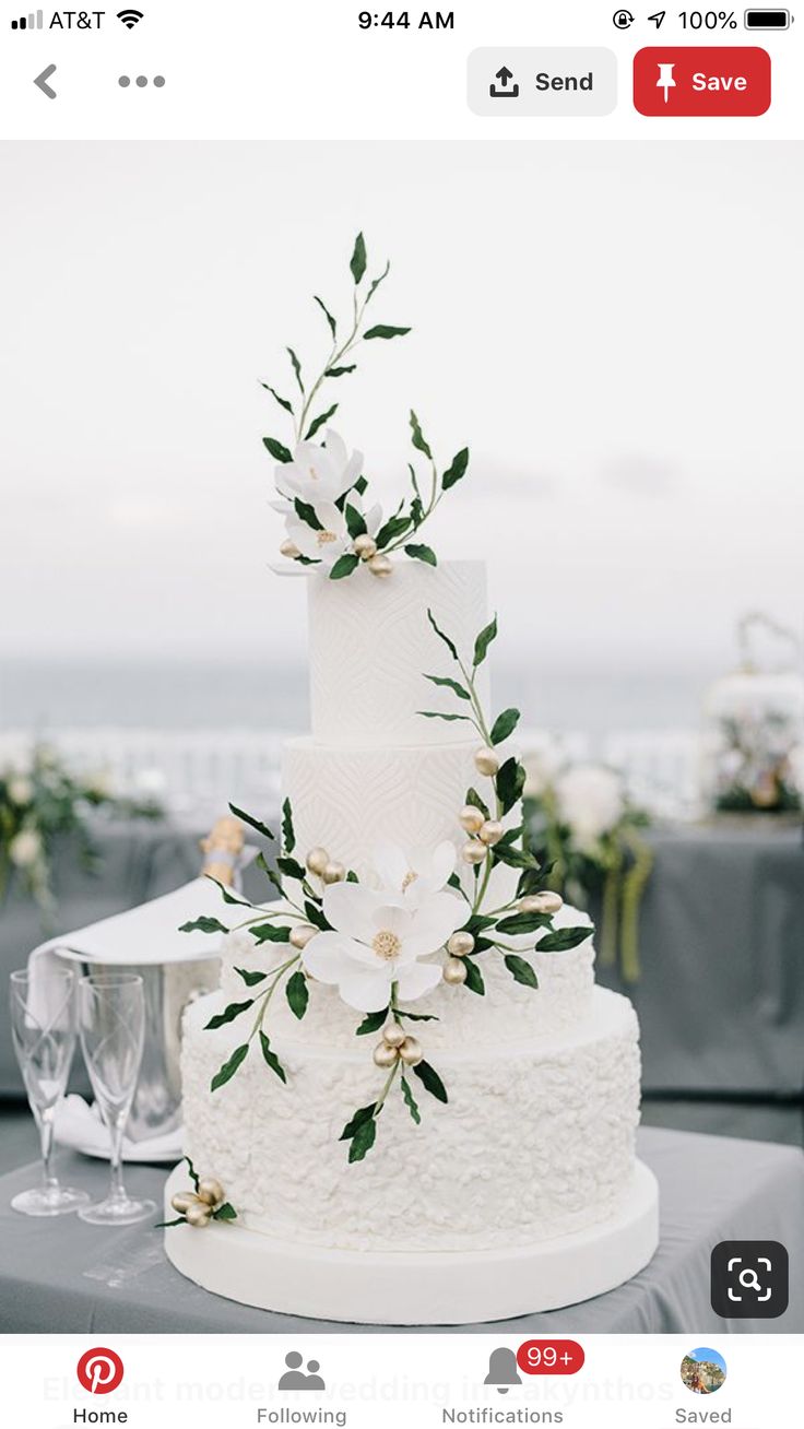 a white wedding cake sitting on top of a table next to a glass of wine