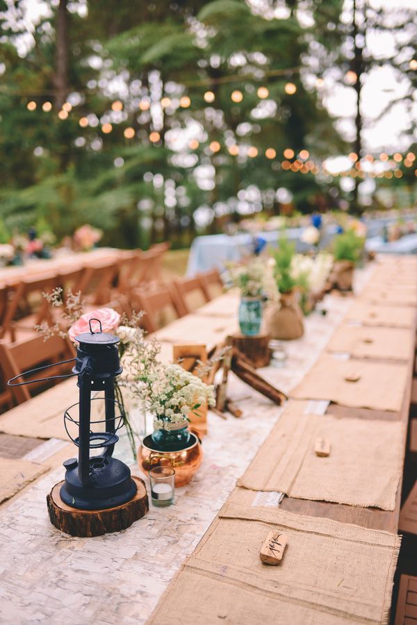 an outdoor table set up with candles, flowers and other items on top of it