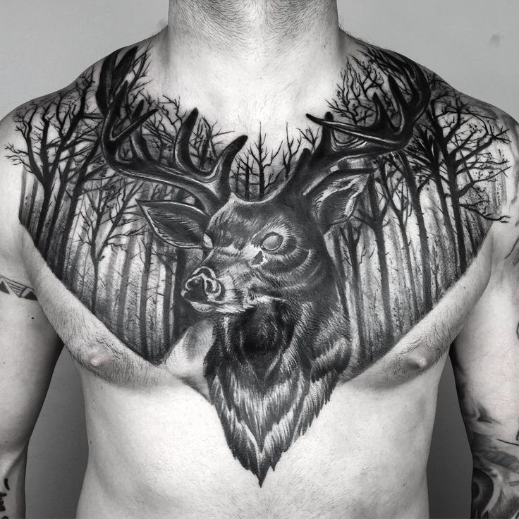 a man with tattoos on his chest has a deer head and trees in the background