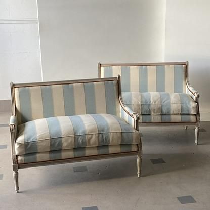 two striped couches sitting next to each other in a room with tile flooring