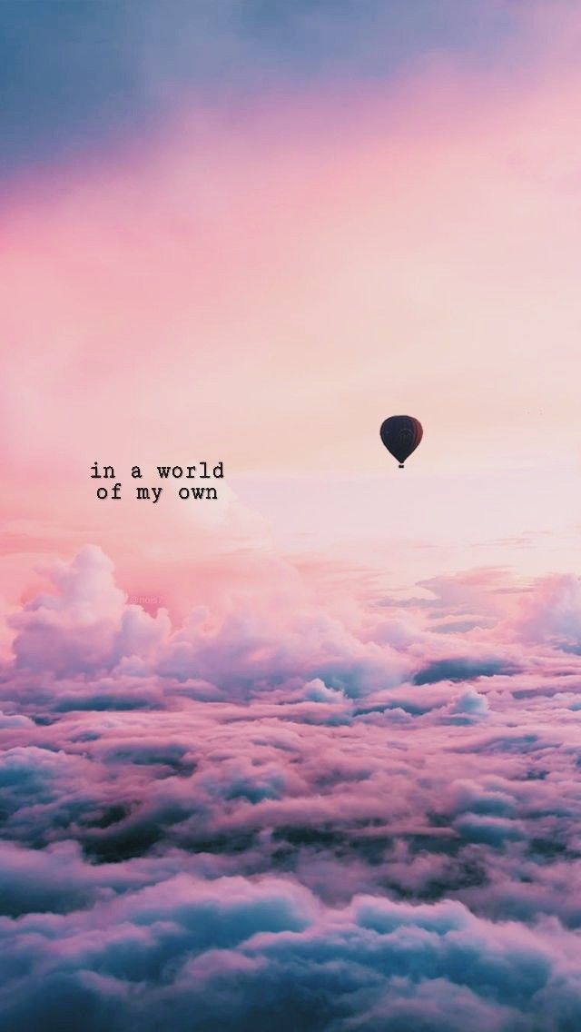 a hot air balloon flying in the sky above clouds with words written on it that says, in a world at my own