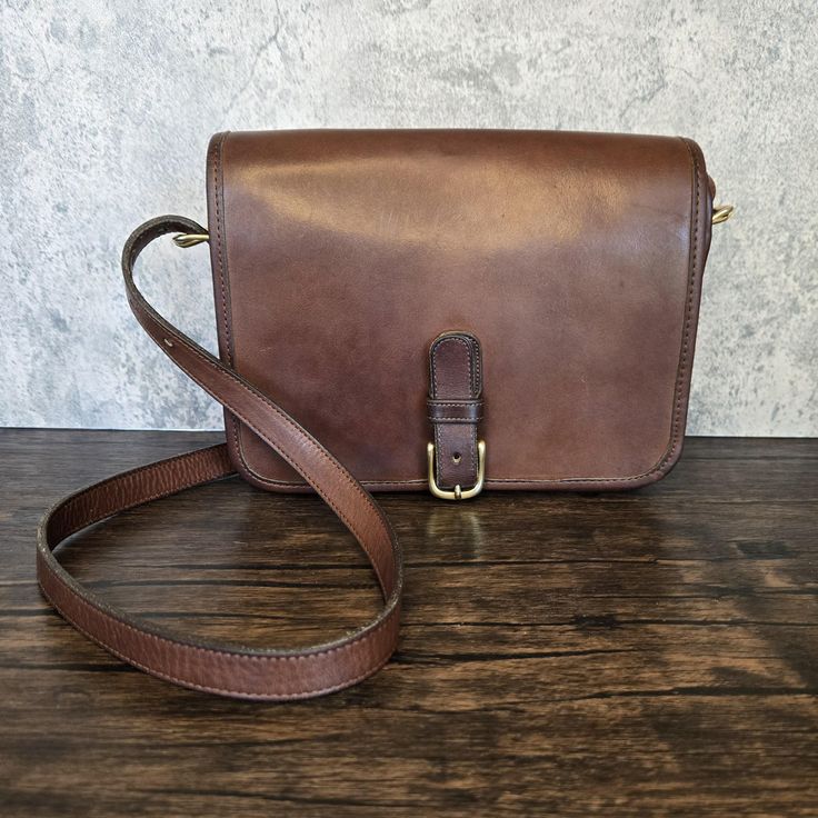 Vintage Coach #9590 Small Buckled Saddle Pouch Crossbody Bag in Tabac Brown Tan Genuine Leather with Raw Suede Interior. 1970's New York City Bag. Solid Brass Hardware. Square Shaped Front Flap that secures via Solid Brass Buckle Closure, Large Pocket Under Flap, and  Inner Zippered Pocket. Adjustable Strap Length. Does not have a Matching Hangtag. Registration #: . #169-9238. Made in New York City, USA in the late 1970s. The Creed, Registration #, and Bag have been authenticated as Genuine Vint Vintage Brown Crossbody Flap Bag, Retro Vintage Brown Crossbody Shoulder Bag, Vintage Brown Retro Crossbody Shoulder Bag, Vintage Brown Shoulder Bag With Cell Phone Pocket, Classic Saddle Bag With Cell Phone Pocket For Travel, Classic Saddle Bag For Travel, Vintage Brown Bag With Cell Phone Pocket, Vintage Rectangular Flap Bag With Adjustable Strap, Vintage Crossbody Flap Bag With Removable Pouch