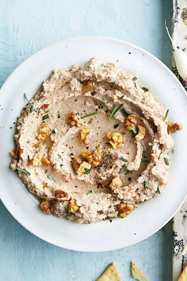 a white plate topped with hummus and crackers on top of a blue table