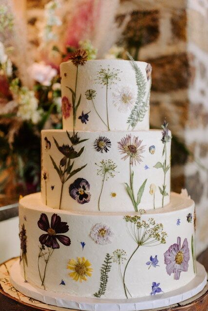 a three tiered cake with flowers painted on it