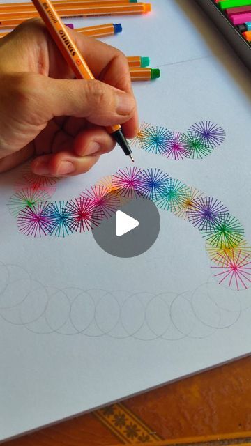 someone is doing something with colored pencils on the paper and they are drawing fireworks