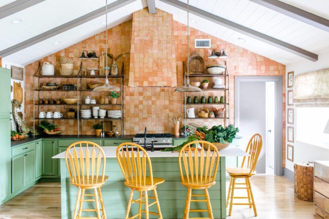 a kitchen with green cabinets and yellow chairs