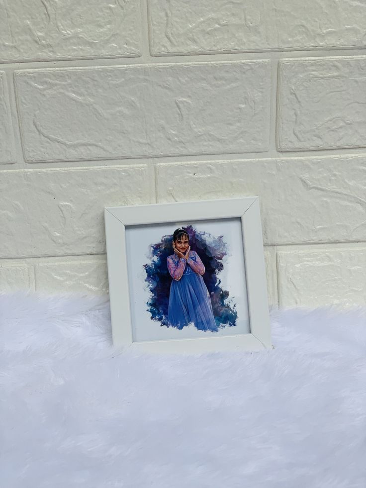 a white frame with a photo of a woman in blue on top of a fluffy surface