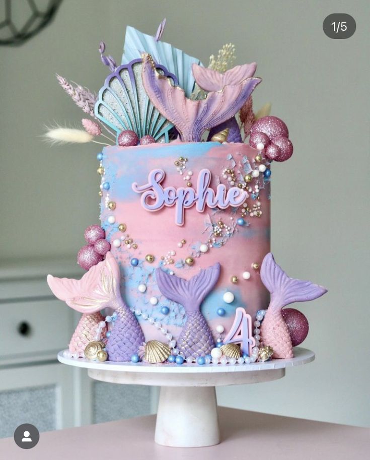 there is a pink and blue cake with mermaid decorations on the top it says sparkle