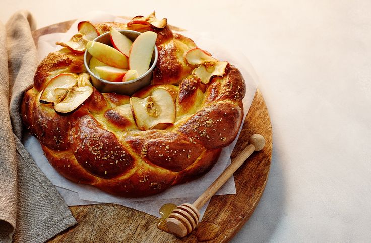 an apple pie on a wooden platter next to a napkin and honey dipper