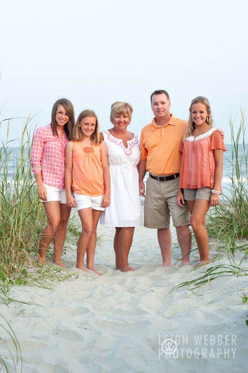 a group of people standing on top of a beach next to tall grass and sea oats