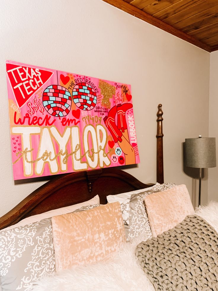 a bed with pillows and a large painting on the wall above it that says taylor