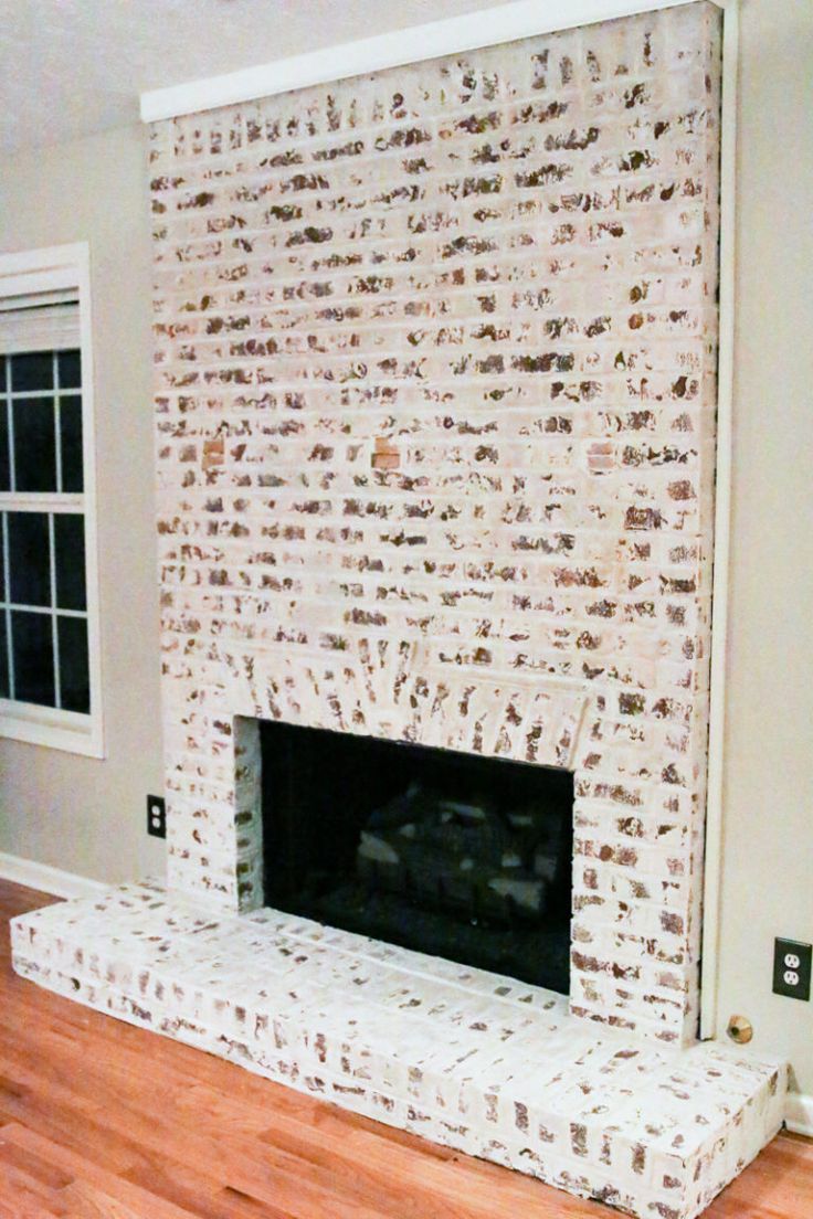 an empty living room with a fireplace and hardwood floors in the middle, all painted white