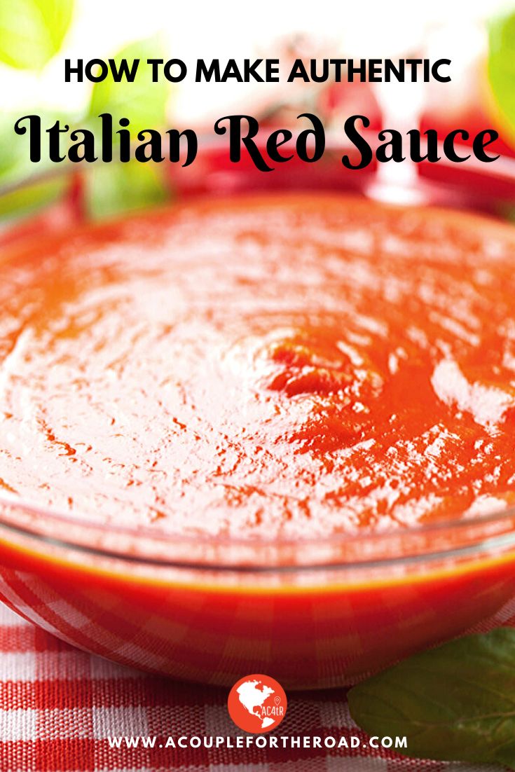 a red sauce in a glass bowl on a checkered table cloth with basil leaves