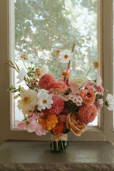 a vase filled with lots of flowers sitting on top of a window sill next to a window