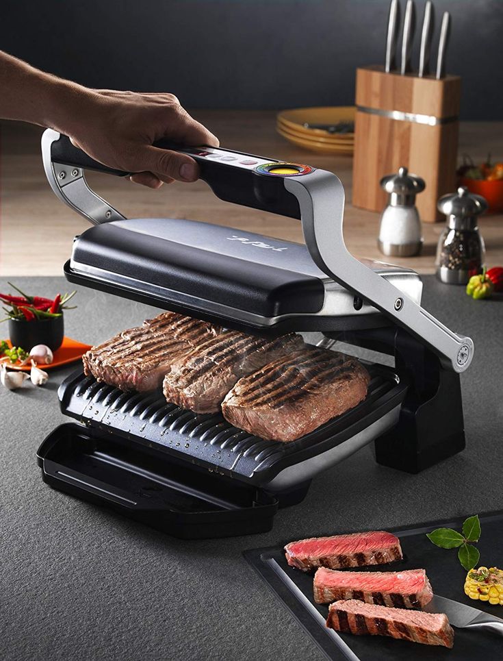 a person is using an electric grill to cook steaks