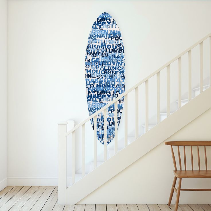 a blue and white surfboard hanging on the wall next to a stair case in a room