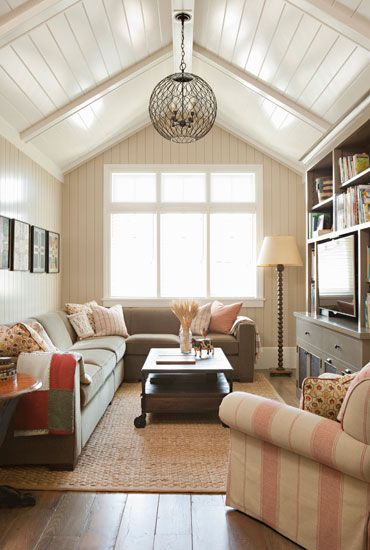 a living room filled with furniture and a chandelier hanging from the vaulted ceiling