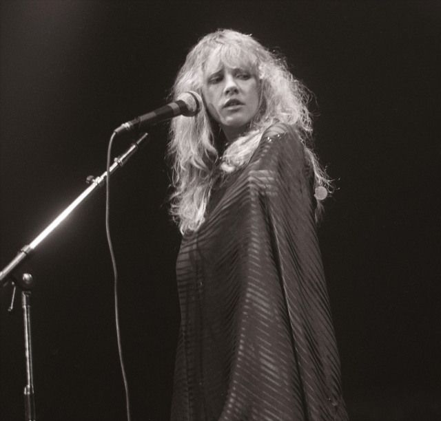 a woman standing in front of a microphone on top of a stage with a mic