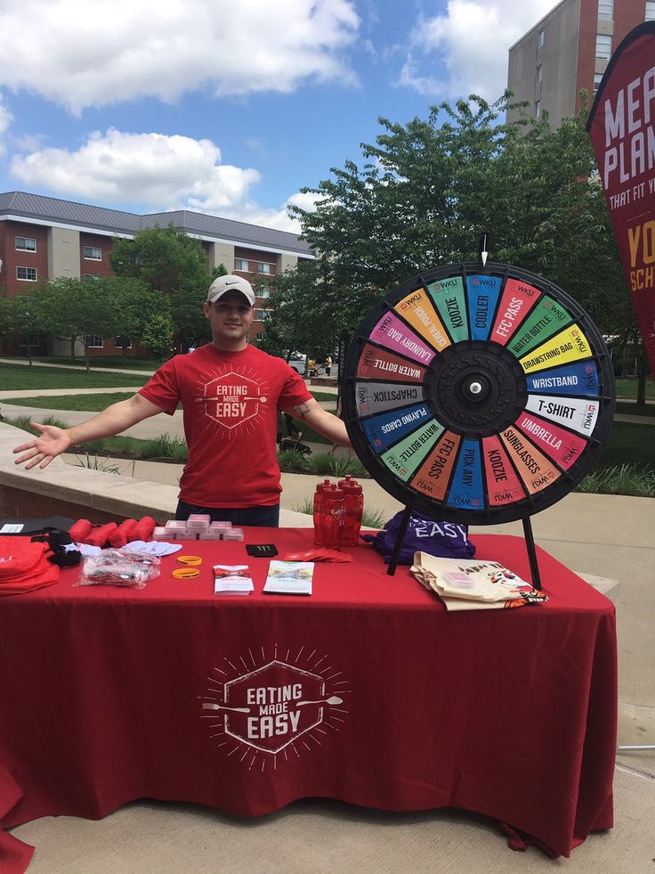 a man standing in front of a red table with a wheel of fortune on it