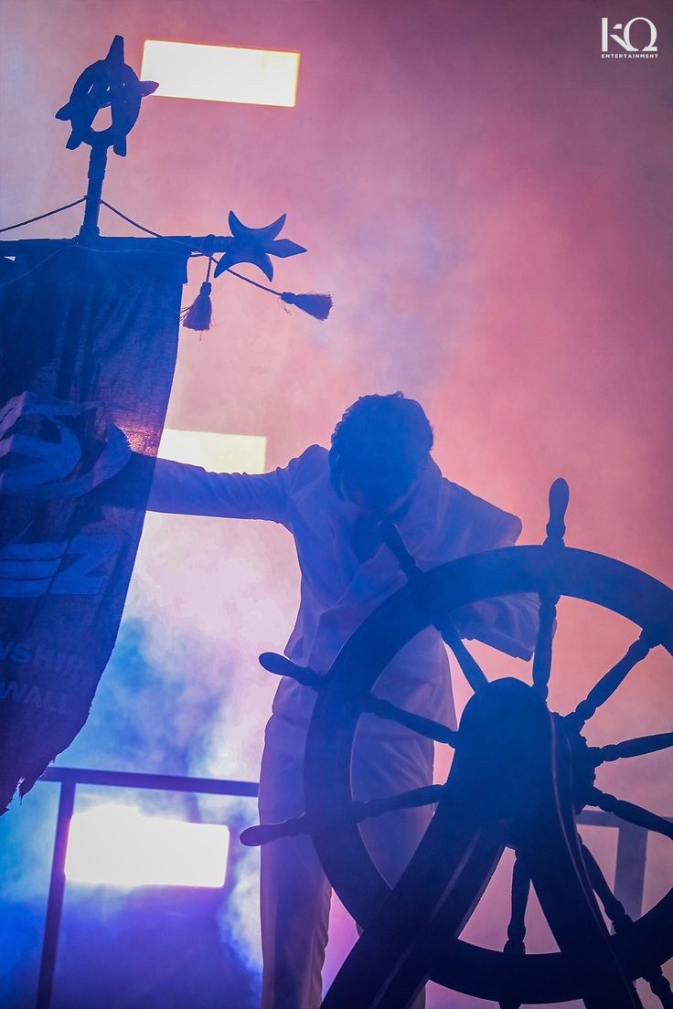 a man standing next to a spinning wheel on stage