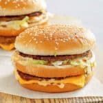 three hamburgers sitting on top of a wooden table