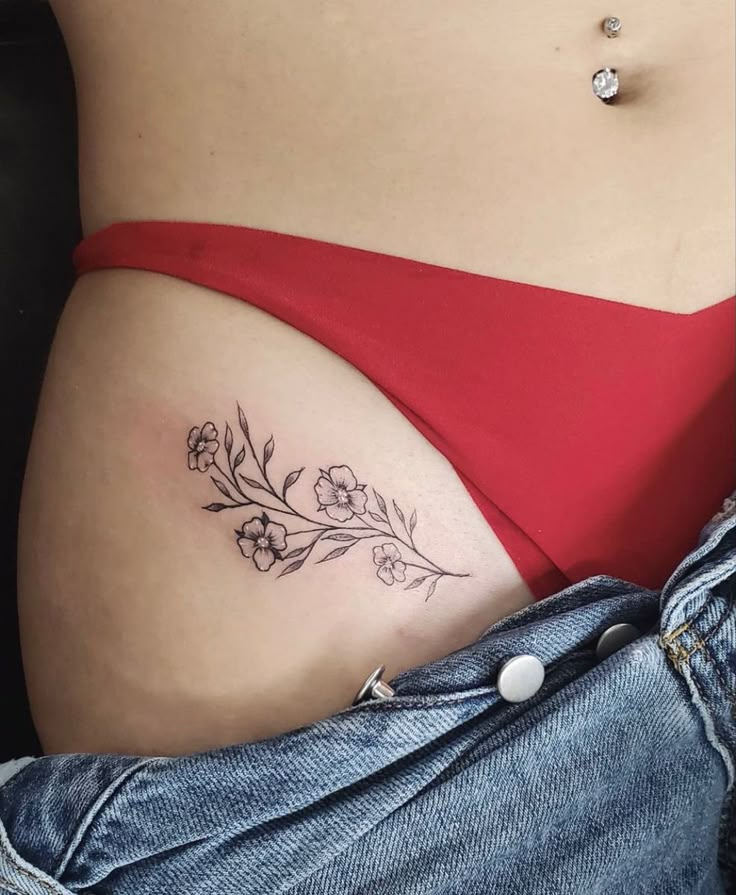 a woman's stomach with flowers and leaves tattooed on her lower side ribcage