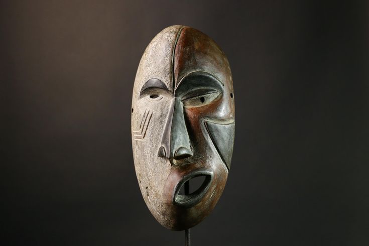 a wooden mask with two faces on it's face and one has a black background