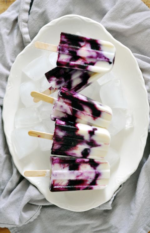 three popsicles on a plate with blue and white swirled toppings, sitting on a table