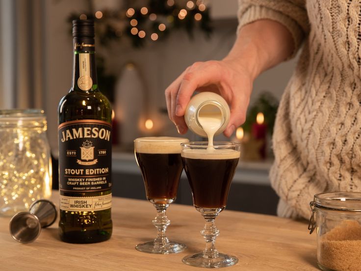 a person pours a drink into two glasses