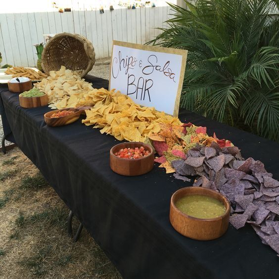 a table filled with chips and dips next to a sign that says chip salad bar