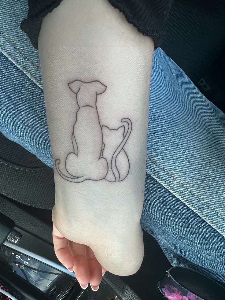 a small dog tattoo on the left inner forearm and foot, sitting in someone's lap