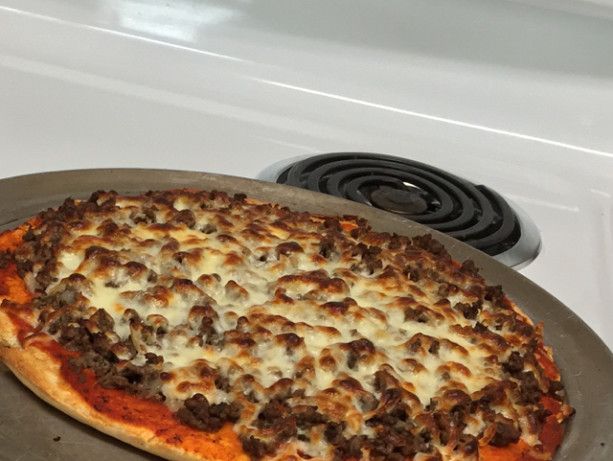 a pizza sitting on top of a metal pan next to an oven burner,