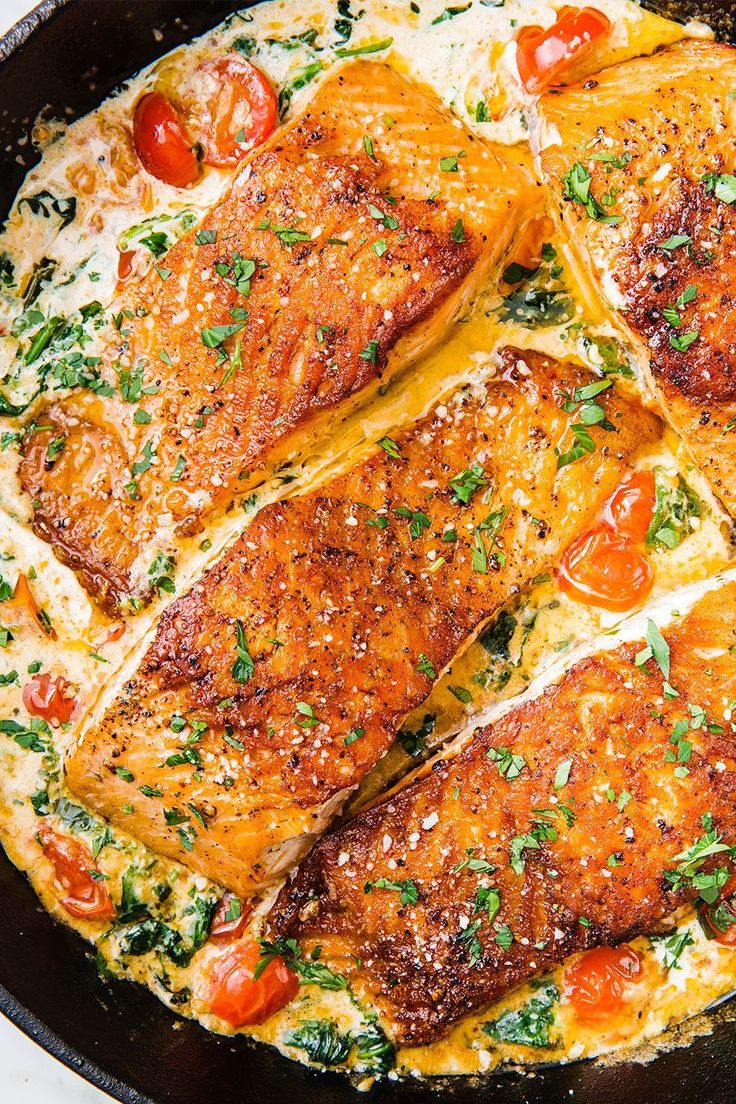 some fish is cooking in a skillet with tomatoes and parmesan cheese on top