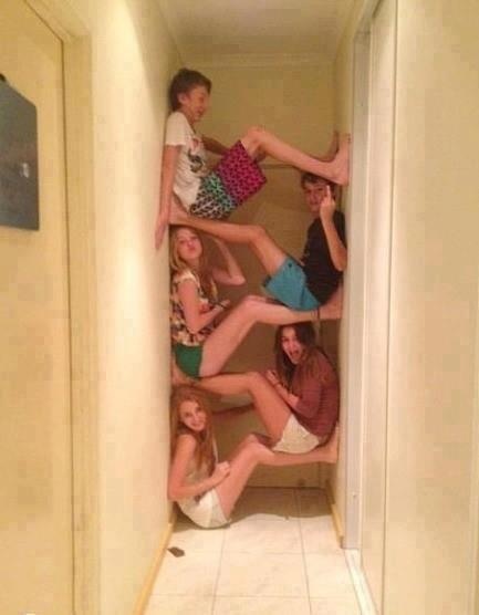 a group of people sitting on top of each other in a hallway next to a toilet