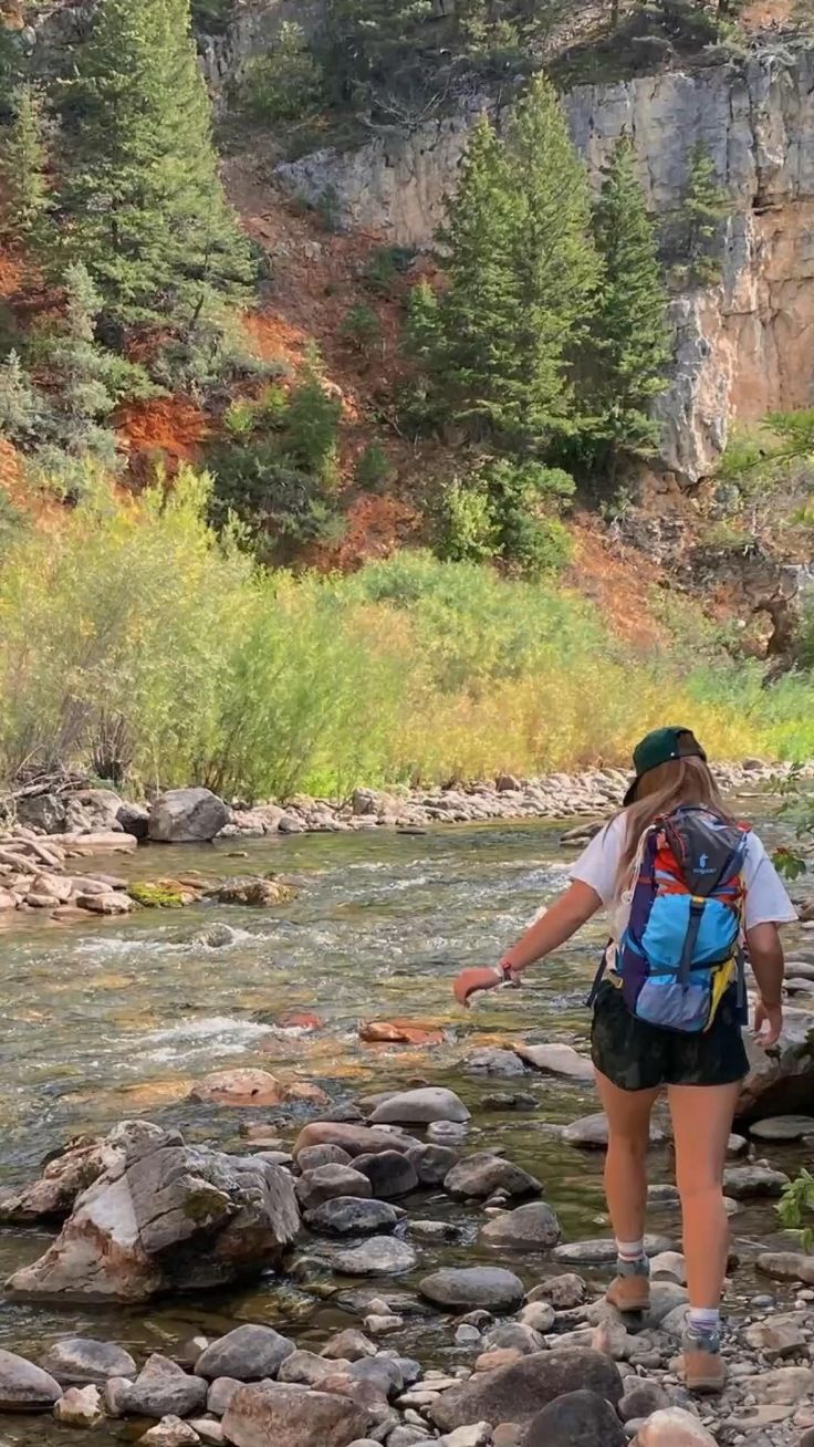 a woman with a backpack crossing a river