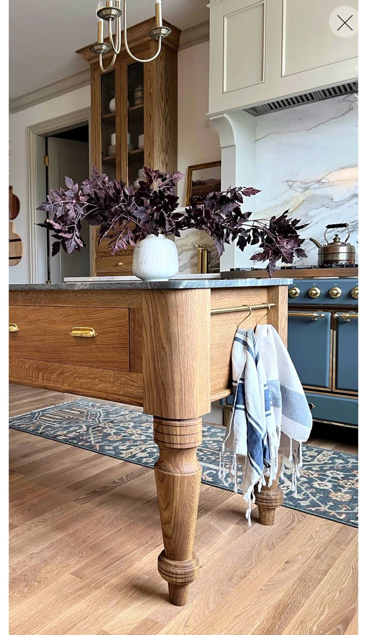 a kitchen island with towels hanging on it's side and potted plants in the center