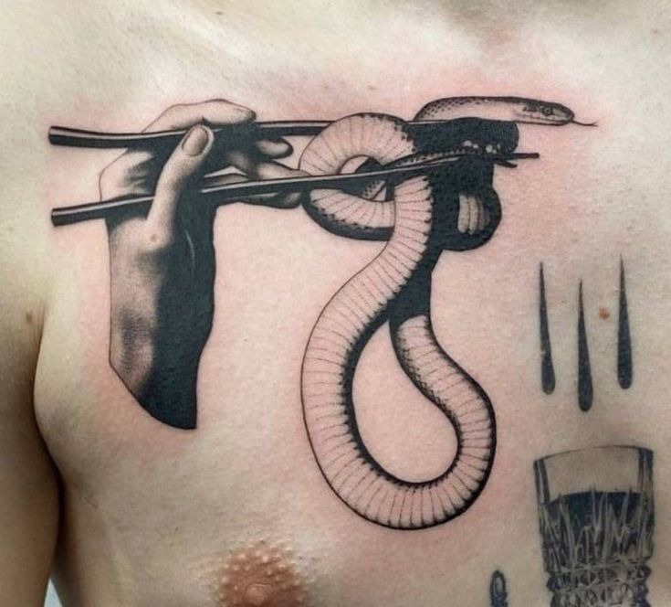 a man's chest with a snake on it and chopsticks in the other hand