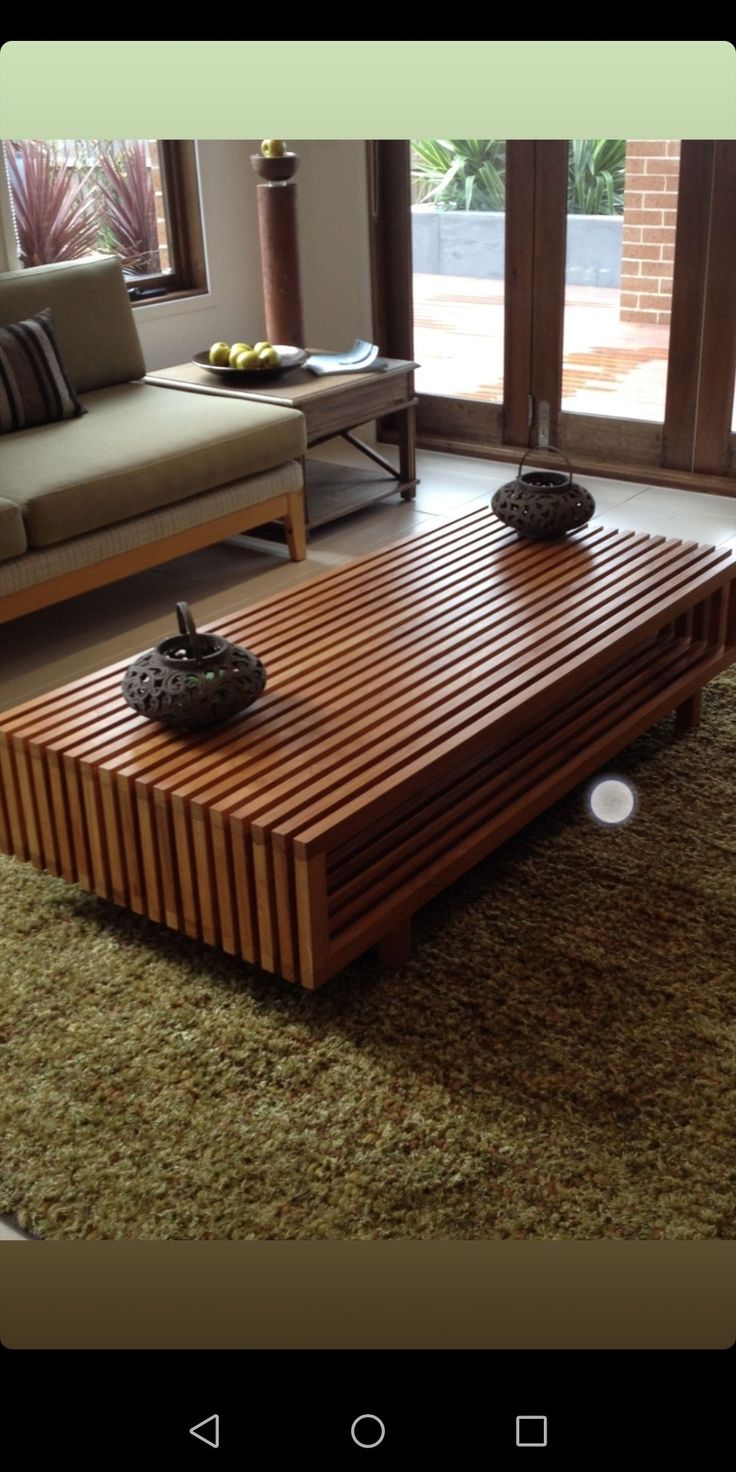 a wooden table sitting on top of a carpeted floor next to a couch and window