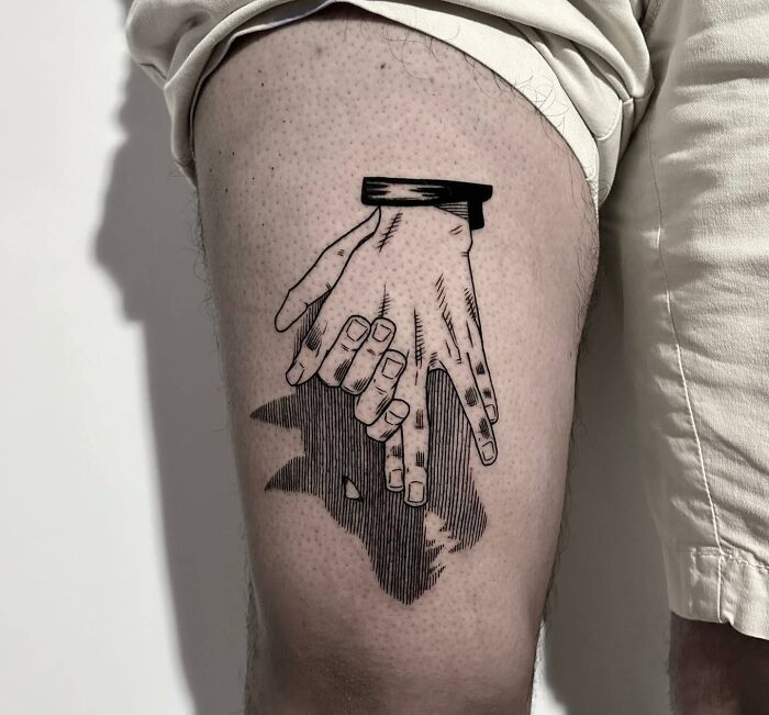 two hands holding each other on the side of a man's thigh with black ink