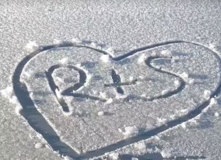 a heart drawn in the snow on top of a field