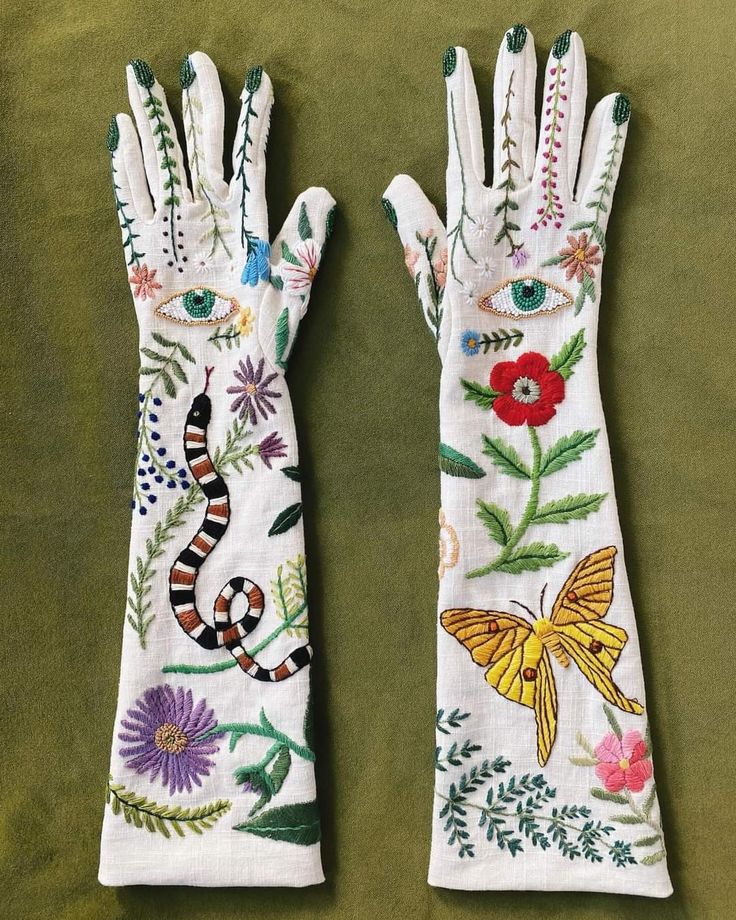 two white gloves with embroidered designs on them, one has a snake and the other is a butterfly