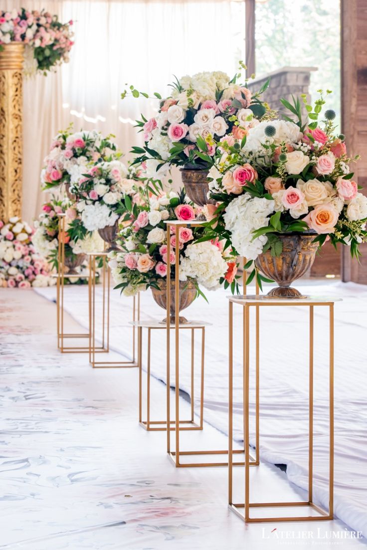 three vases with flowers are lined up on the floor in front of each other